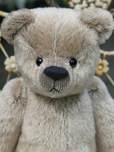 a brown teddy bear sitting on top of a wooden table next to some white flowers