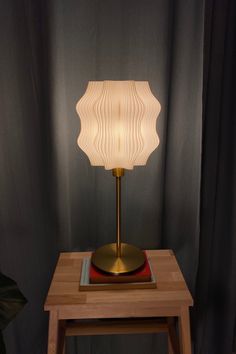 a table lamp sitting on top of a wooden table next to a curtained window