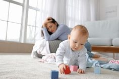 a baby playing with blocks on the floor in front of a woman laying on the floor