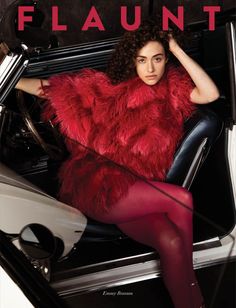 a woman is sitting in a car wearing a red fur coat and black tights