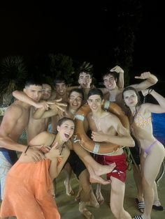 a group of people standing next to each other in front of a pool at night