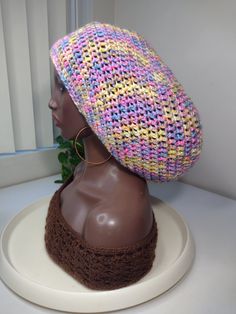 a brown mannequin head wearing a multicolored knitted hat on top of a white table