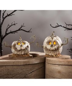 two pumpkins with yellow eyes sitting on top of wooden boxes