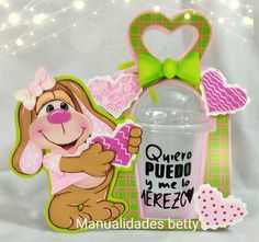 a pink cup with a green bow on it next to a sign that says quero puedo y'me neezy