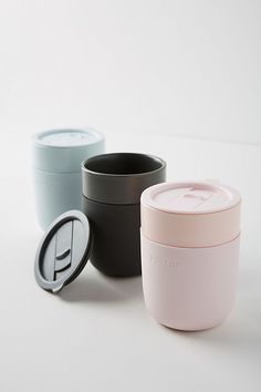 three different colored cups sitting next to each other on a white surface with one cup in the middle