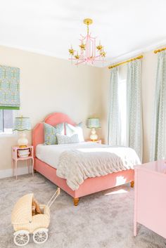 a baby's bedroom with pink furniture and decor on the walls, along with a chandelier