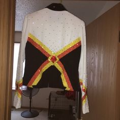 a white and black jacket with gold sequins hanging from a hook in a doorway