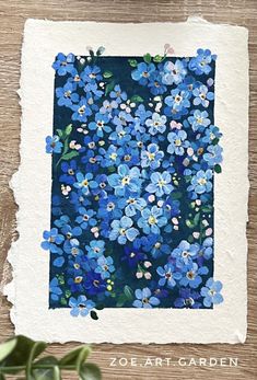 blue flowers are painted on paper and placed on a wooden surface with the words ze art garden