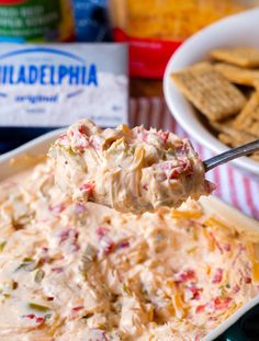 a spoon full of dip with crackers in the background