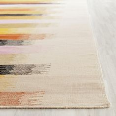 a multicolored rug on the floor with white wood floors and light colored carpeting