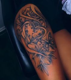 a woman's arm with a clock and flowers tattoo on her left side, next to a black chair