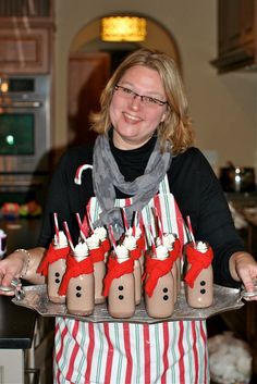 a woman is holding a tray with cupcakes in the shape of snowmen