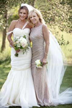 two beautiful women standing next to each other in front of trees and grass wearing dresses