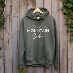 Grab this Mountain Seeker essentials hoodie to take with you on your next adventure or camping trip into nature!  Available in 6 colors choices! (Also available as a sweatshirt and t-shirt in shop.) ---- Production and Shipping ---- Production times are 2-7 business days All orders are received First Class (no UPS/FedEx) Shipping times may take an additional  3-5 days within the U.S. 5-10 days to Canada  *10-20 business days internationally ---- Apparel Info ---- We only use high quality shirts Hooded Sweatshirt With Kangaroo Pocket For Outdoor Activities, Hoodie Sweatshirt With Kangaroo Pocket For Outdoors, Fall Hiking Hoodie With Kangaroo Pocket, Outdoor Hoodie With Kangaroo Pocket, Hoodie With Kangaroo Pocket For Outdoor Activities, Hoodie With Adjustable Hood For Outdoor Activities, Fall Hiking Sweatshirt With Kangaroo Pocket, Letter Print Hoodie For Adventure In Fall, Outdoor Hoodie With Adjustable Hood