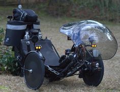 a black motorcycle parked on top of a grass covered field next to a bush and trees