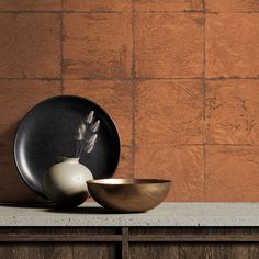 two bowls and a plate sit on a counter in front of a brown brick wall