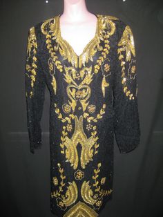 "This beautiful black and gold pageant style gown has long sleeves and a V neckline and hits at  below the knee. This gown has gold sequin and bead all over front on side sleeve and back neck line. Measurements for this gown in a  Size=12   Bust-42\", Waist-38\", Hip-44\", Length-40\" Size=14   Bust-43\", Waist-38\", Hip-45\", Length-40\" Size=16   Bust-45\", Waist-40\", Hip-46\" Length-39\" Since we do not offer refunds or exchanges, please contact us with any questions prior to checkout to ens Black And Green Dress, Stunning Gowns, Feather Dress, Star Dress, Gold Sequin, Dress Clothes For Women, Houston Tx, Black And Gold, Green Dress