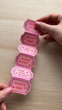 two hands are holding pink tickets with words on them that read movie night and have hearts