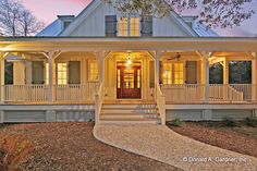 a large white house with porches and steps leading to the front door at night