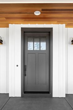 the front door of a house with two lights on each side and one light on the wall