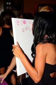 a woman writing on a white board in front of other women at a party or social gathering