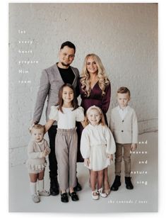 a family posing for a photo in front of a white wall with words on it