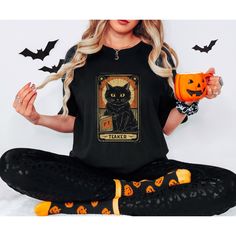 🔮 Embrace Your Feline Destiny with the Tarot Cat Shirt! 🔮 Conjure up a fashion statement like no other with our enchanting Black Cat Halloween Shirt! Featuring a single captivating black cat tarot card, this Witchy Shirt is the epitome of spooky elegance. Crafted on Comfort Colors Halloween TShirt, this Fall Cat Shirt boasts unparalleled comfort while adding a touch of mysterious charm to your outfit. The Spooky Black Cat design will leave you feeling bewitched, setting the perfect tone for th Cute Black T-shirt With Cat Design, Shirt Knot, Spooky Cat Design T-shirt For Fall, Spooky Black T-shirt With Cat Design, Spooky Halloween T-shirt With Cat Design, Halloween Black T-shirt With Cat Design, Ghost Gifts, Black Halloween T-shirt With Cat Design, Casual Halloween Cat Design T-shirt