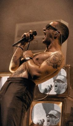 a shirtless man singing into a microphone