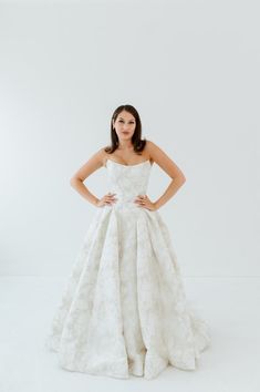 a woman in a white wedding dress posing for the camera with her hands on her hips