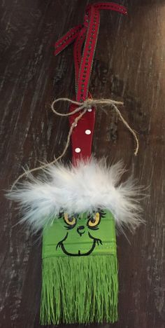 an ornament made to look like a green monster with white feathers and a red handle