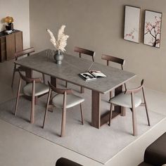 a dining room table with chairs and a vase on the top, next to a couch