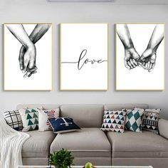 three framed pictures hanging on the wall above a couch in a living room with two people holding hands