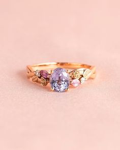 a gold ring with three different colored stones on it's sides and the center stone is