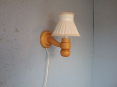 a lamp that is on the wall next to a white light fixture with a wooden arm