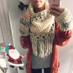 a woman taking a selfie in front of a mirror wearing a santa hat and scarf