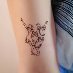 a small tattoo on the arm of a woman's leg, depicting two dancers