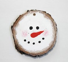 a piece of wood with a painted snowman on it's face and red nose