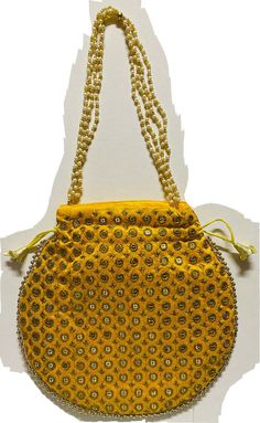 a yellow purse with beads hanging from it's side on a white wall background