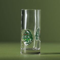 a shot glass with a green and red design on the side, sitting on a table