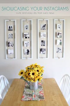 a wooden table topped with a vase filled with sunflowers next to pictures on the wall