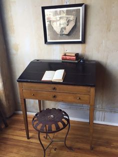 a desk with a book on it in front of a painting and a framed photo