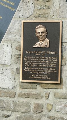 a plaque on the side of a stone wall that has a portrait of a man