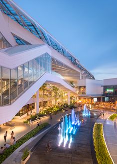 an aerial view of a modern building with fountains in the foreground and people walking around