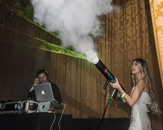 a woman in a white dress is holding a microphone and standing next to a man with a laptop