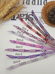 several different colored bracelets sitting on top of a table next to a pine cone