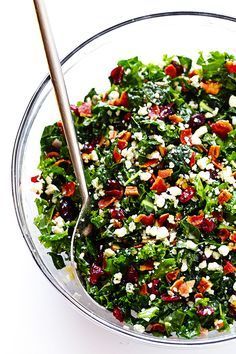 a white bowl filled with greens and cranberries