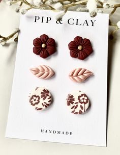 three different flower shaped buttons sitting on top of a piece of white and brown paper