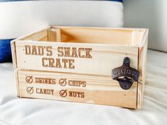 a wooden crate sitting on top of a bed with the words dad's snack crate