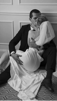 a man in a tuxedo and woman in a wedding dress sitting on the floor