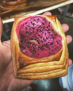 a hand holding a piece of bread with a pink substance on it